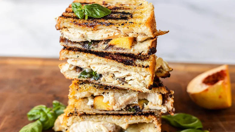 Chicken, Brie, and Peach Panini stacked on wooden cutting board