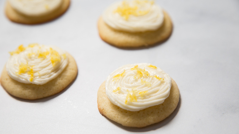 four frosted lemonade cookies with lemon zest on table