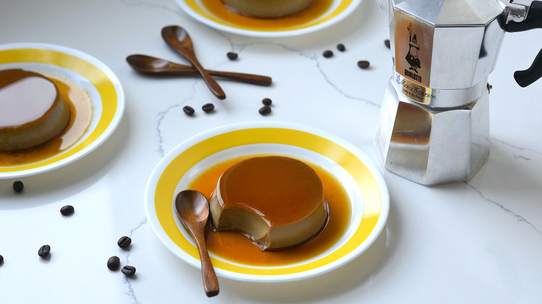 Coffee purin (Japanese custard pudding) in the foreground with a moka pot and scattered coffee beans in the background