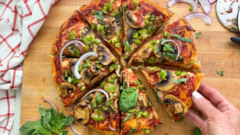 hand grabbing slice of pizza