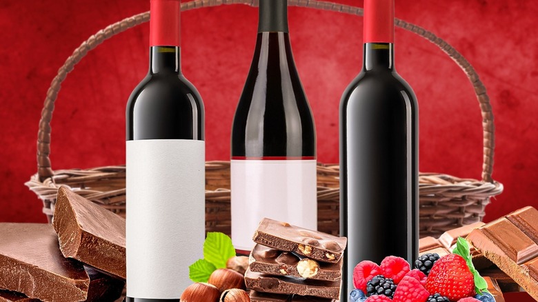 Three unbranded wine bottles with various chocolates and a basket