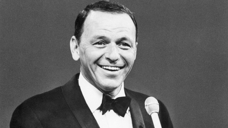 A black and white photograph of Frank Sinatra holding a microphone