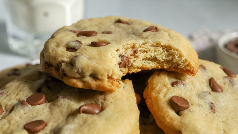 chocolate chip cookie with bite taken on top of chocolate chip cookies