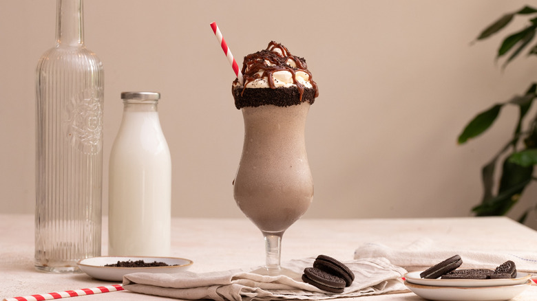 Cookies and cream milkshake next to Oreos and jug of milk