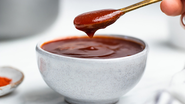Spooning BBQ sauce from small grey bowl