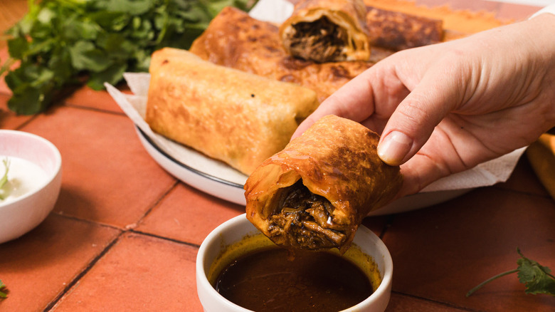 Dipping chimichanga half into consomme