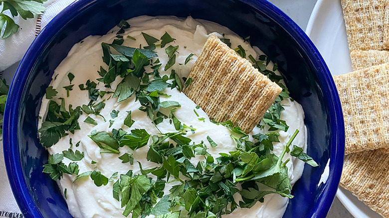 Bowl of whipped feta dip with parsley and crackers