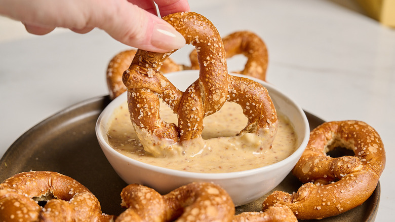 dipping a pretzel into honey mustard sauce