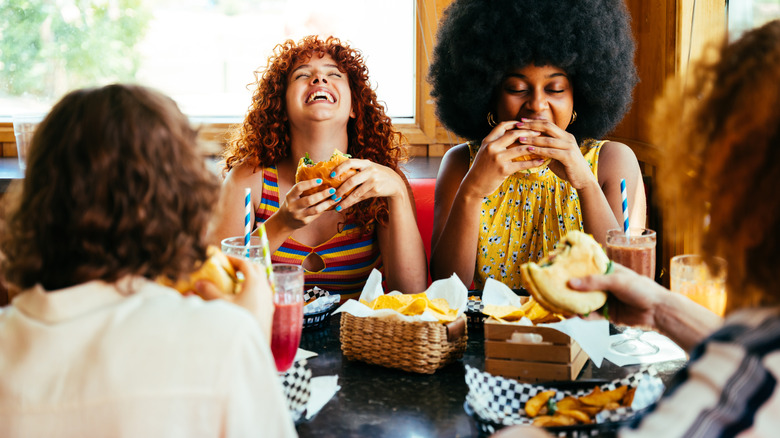 Four women laughing and enjoying food in a retro diner