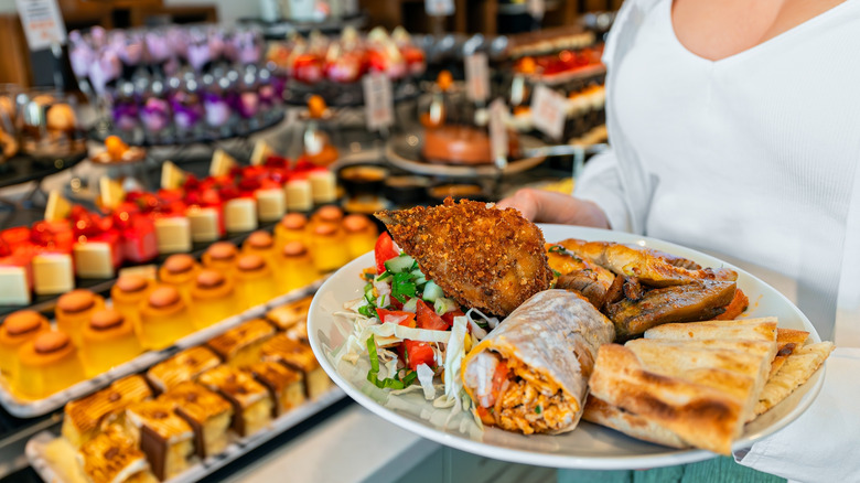 A woman holding a plate of food at a buffet
