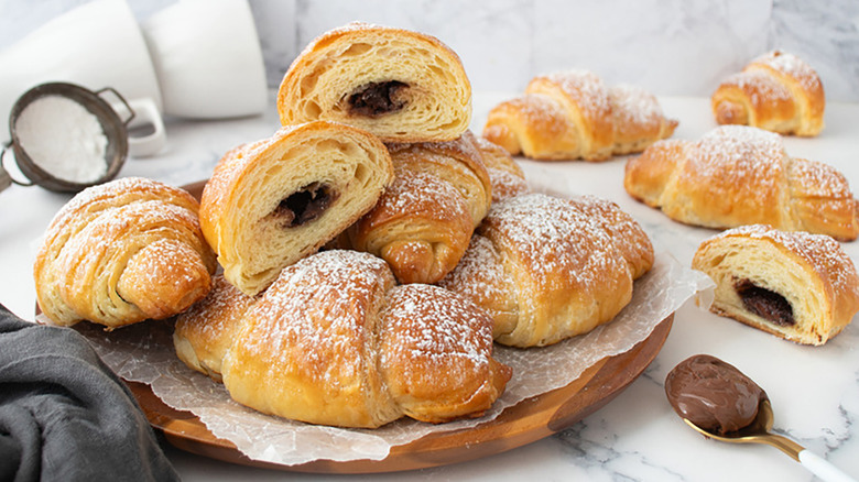 Pile of Nutella-stuffed croissants on parchment-lined wooden platter