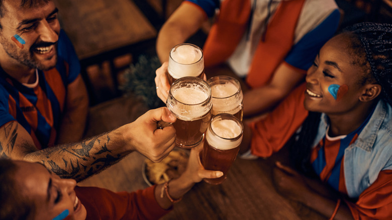 Group of friends wearing red, white, and blue toasting beers in bar