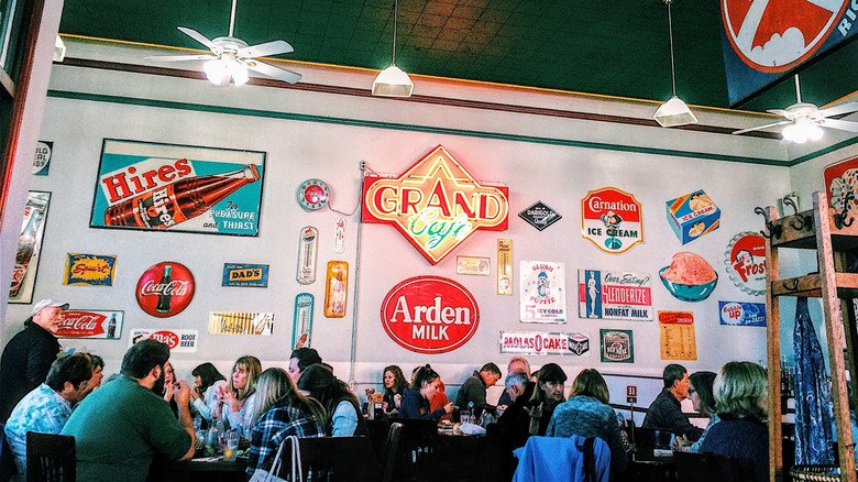 Restaurant interior with neon signs on the walls and people at the tables