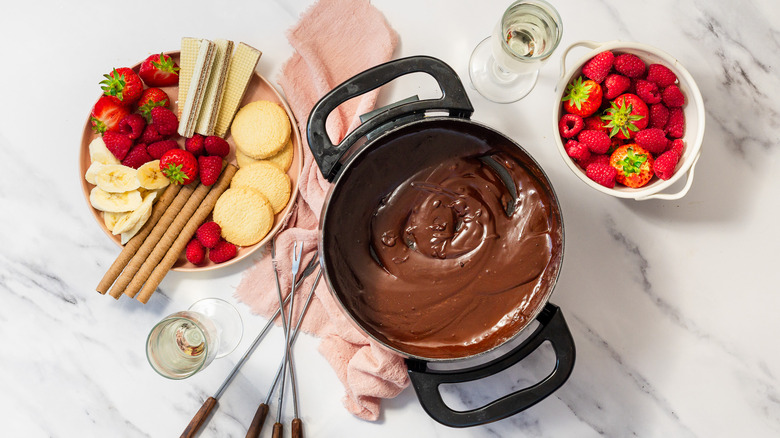 Chocolate fondue for two with berries, cookies, and two champagne glasses