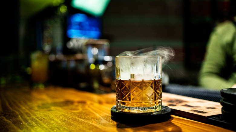 Smoky whiskey cocktail on bar with blurred background