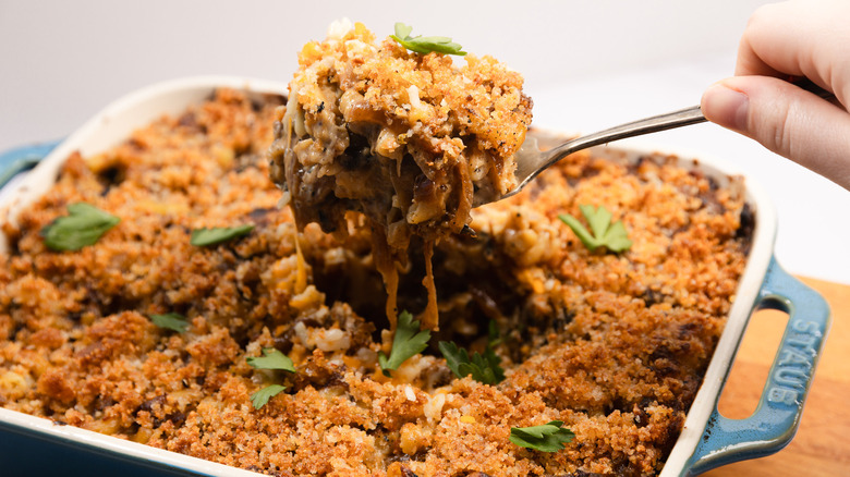 Lifting a serving of French onion mac and cheese from a casserole dish