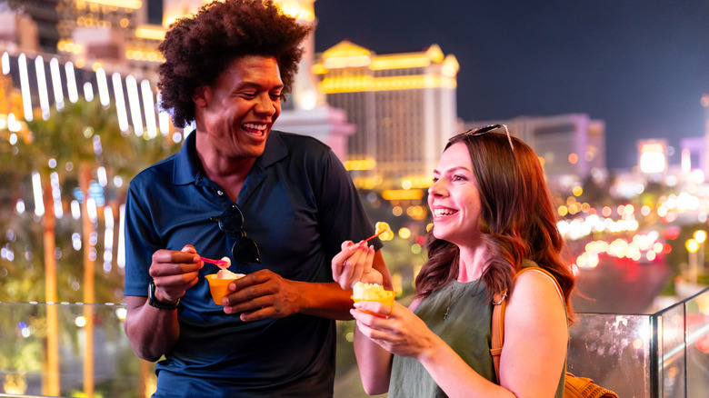 Two people eating snacks on bridge of the Strip at night