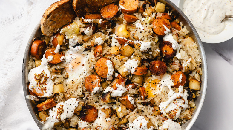 Skillet with potatoes, sausage, eggs, and mustard remoulade sauce on the side