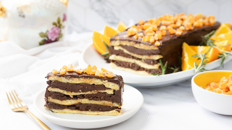 Slice of 7-layer chocolate orange passover cake with cake in background