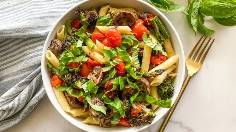 Bowl of spring pasta salad with asparagus, mushrooms, basil, and broccoli