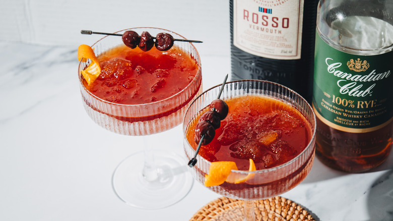 Overhead view of two frozen Manhattan cocktails with two liquor bottles.