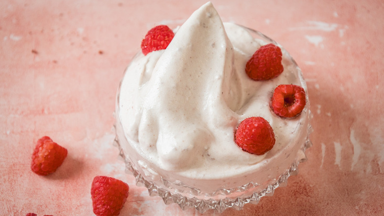 Raspberry marshmallow fluff in glass container with fresh raspberries