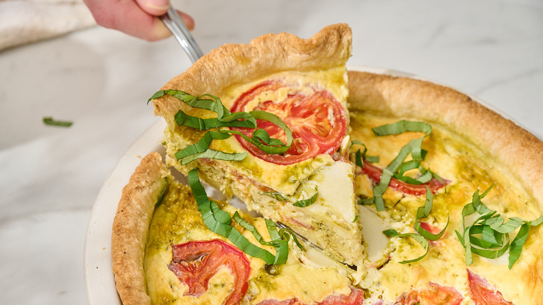 Lifting slice of caprese quiche out of pan