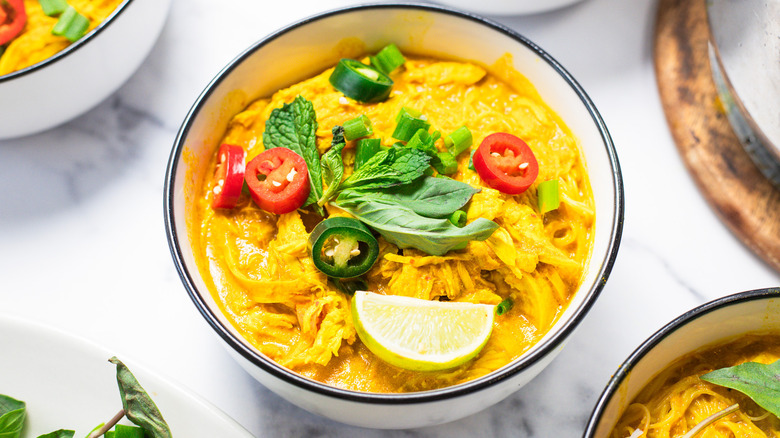 Bowl of coconut curry chicken noodle soup with extra bowls around.