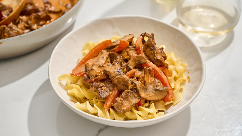 Beef stroganoff over noodles in a bowl