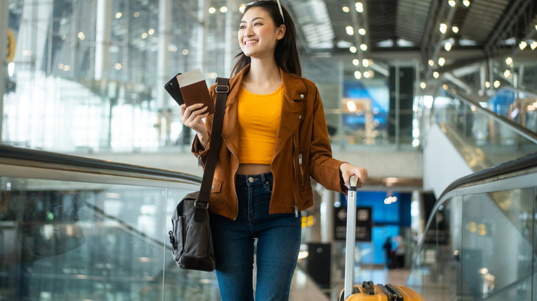 Smiling woman at an airport with a suitcase