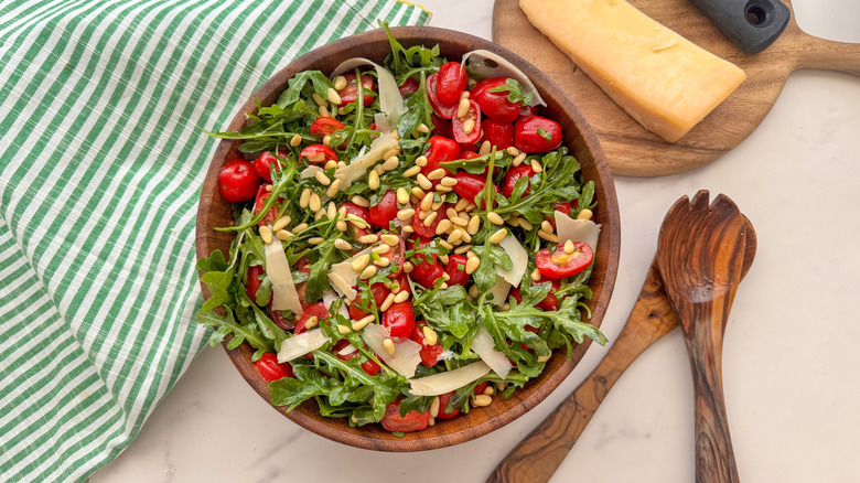 Marinated tomato and arugula salad in wooden bowl