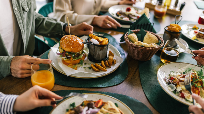 People at restaurant table with burgers, fries, drinks