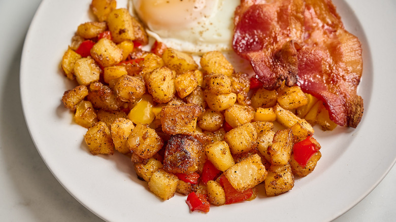diner-style home fries on a plate with eggs and bacon