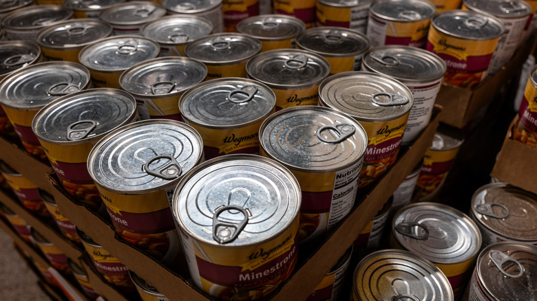 Several stacked cardboard crates of canned soup, with the labels of other of them showing the word 