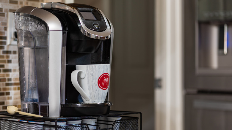 A Keurig coffee maker with a full water reservoir and a coffee mug on the brew plate