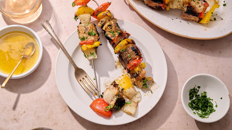 salmon kebabs on a plate with a fork and garnishing on the side