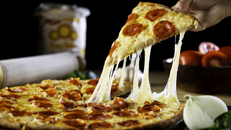 person pulling a slice of pepperoni pizza