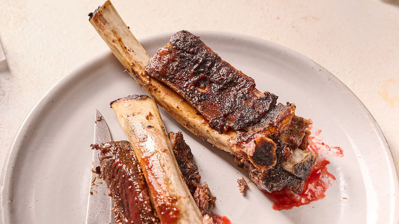 Two tender raspberry chipotle ribs slathered with sauce on a white plate