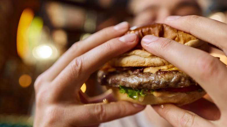 close-up photo of a person holding a burger with both hands