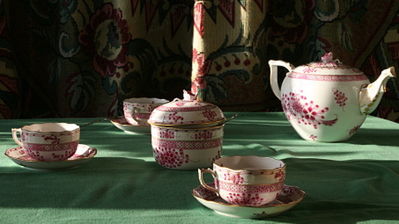 A vintage Mottahedeh teapot and cups set on a table.