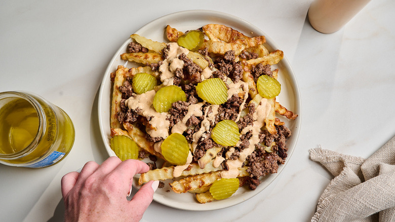 Plate of fries with ground beef and pickles