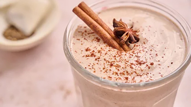 Vanilla chai smoothie in a glass, garnished with a cinnamon stick and star anise