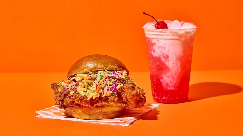 Minnie Bird chicken sandwich and a dirty soda against orange background