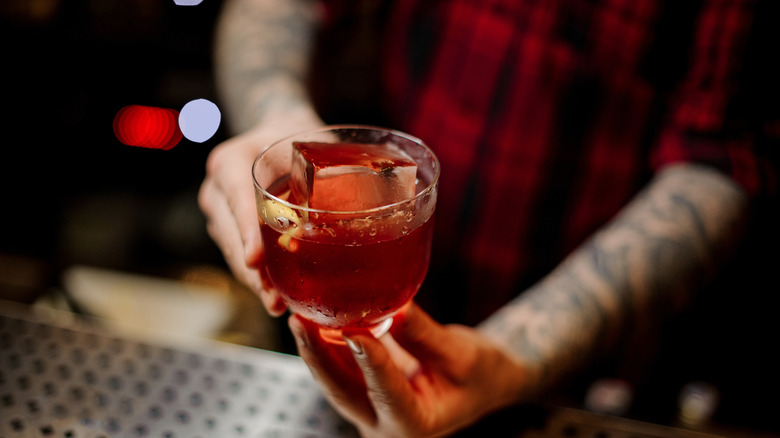 A bartender holding a Vieux Carre cocktail