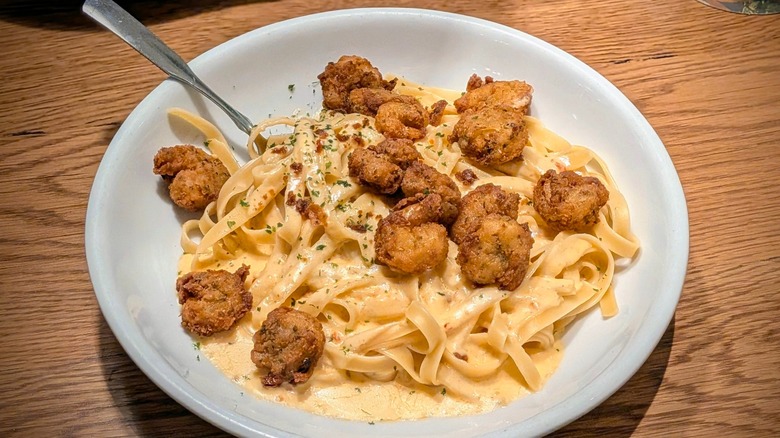 Fettucini with crispy shrimp and spicy Alfredo in a white bowl with a spoon in it