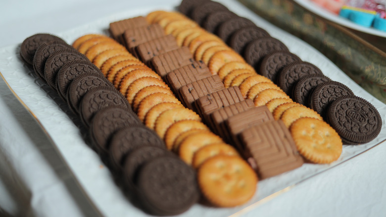 A plate with rows of oreos, crackers, and chocolate cookies