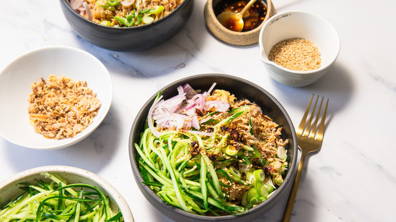 Serving of spicy peanut noodles with all the toppings around