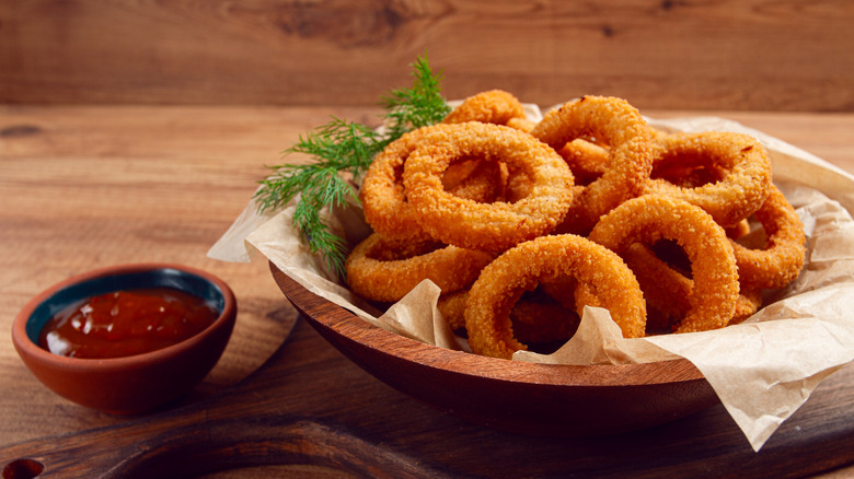 A bowl of onion rings with a side of ketchup