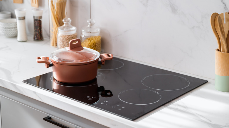 A modern new induction cooktop with a pink pot sitting on top of it