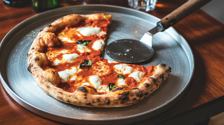 Closeup of a personal margherita pizza on a metal tray.